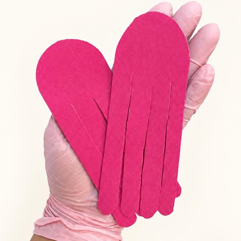 Mão com luva segurando duas fitas rosa de taping recortadas em tiras, no formato da técnica em polvo.