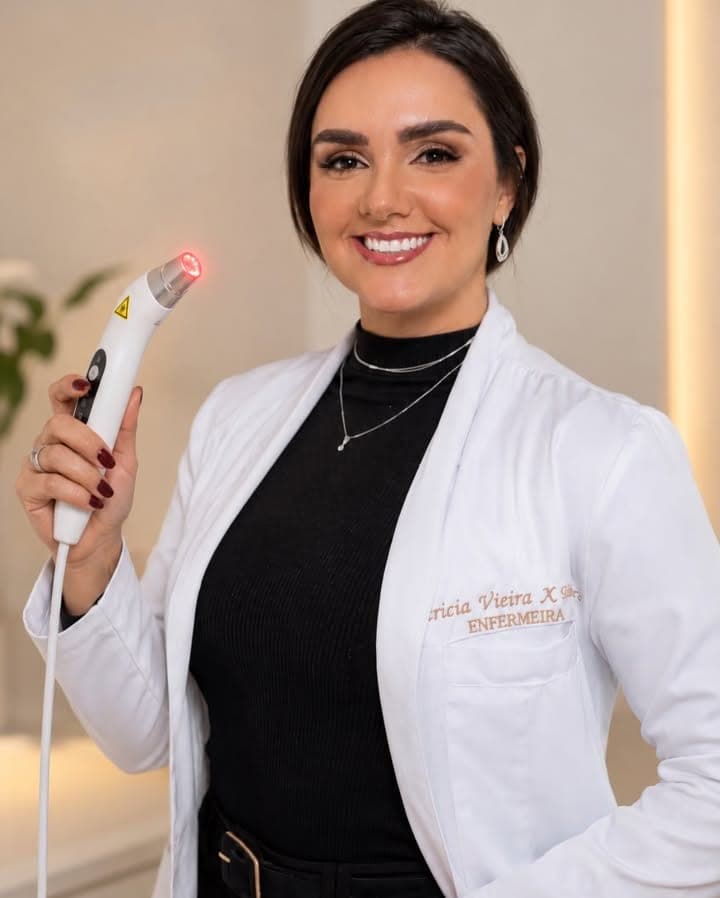Patrícia de jaleco, sorrindo, segurando o aparelho de laserterapia com a luz vermelha acesa.